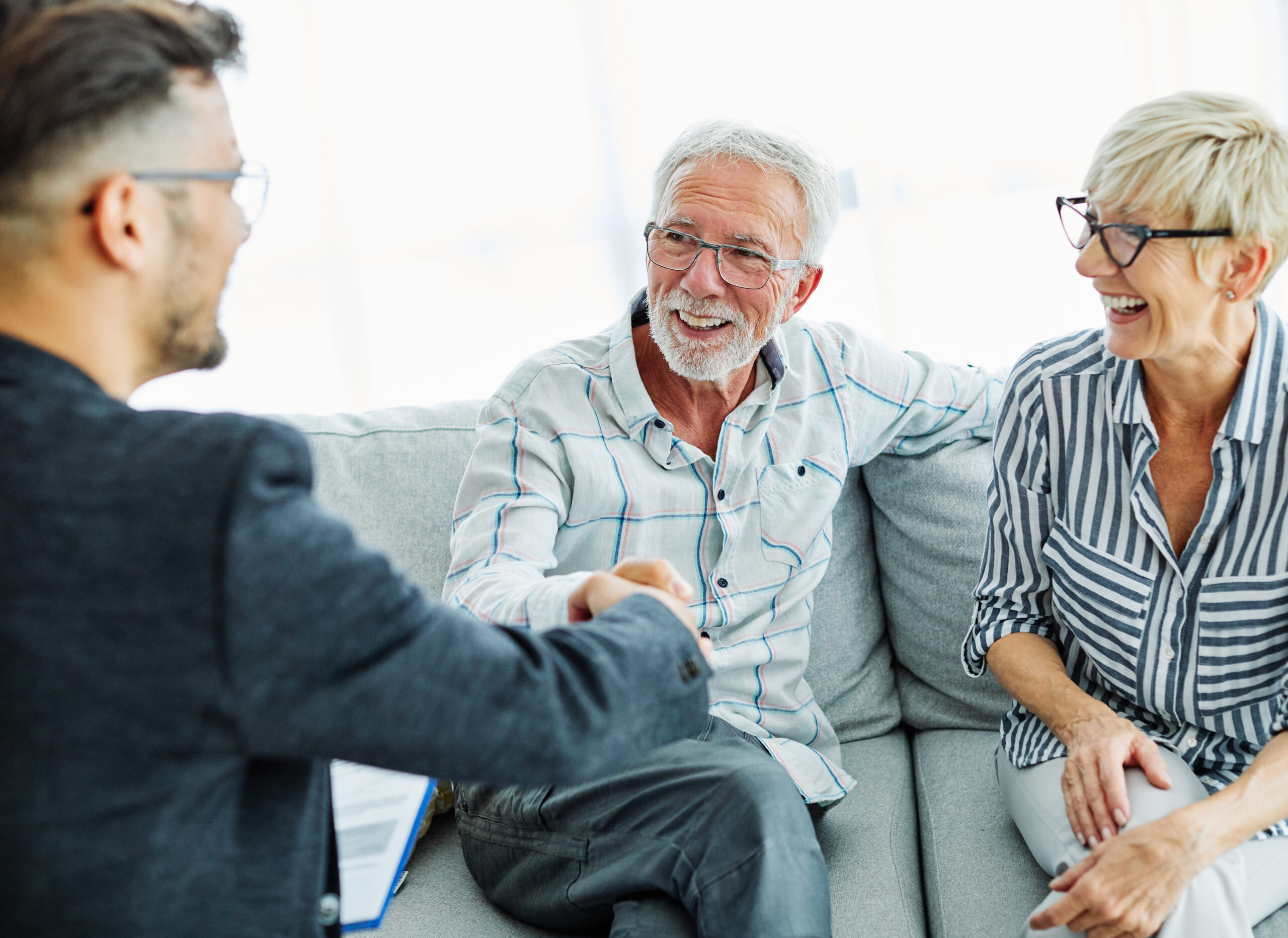 Conseiller serrant la main d'un couple de retraités souriants