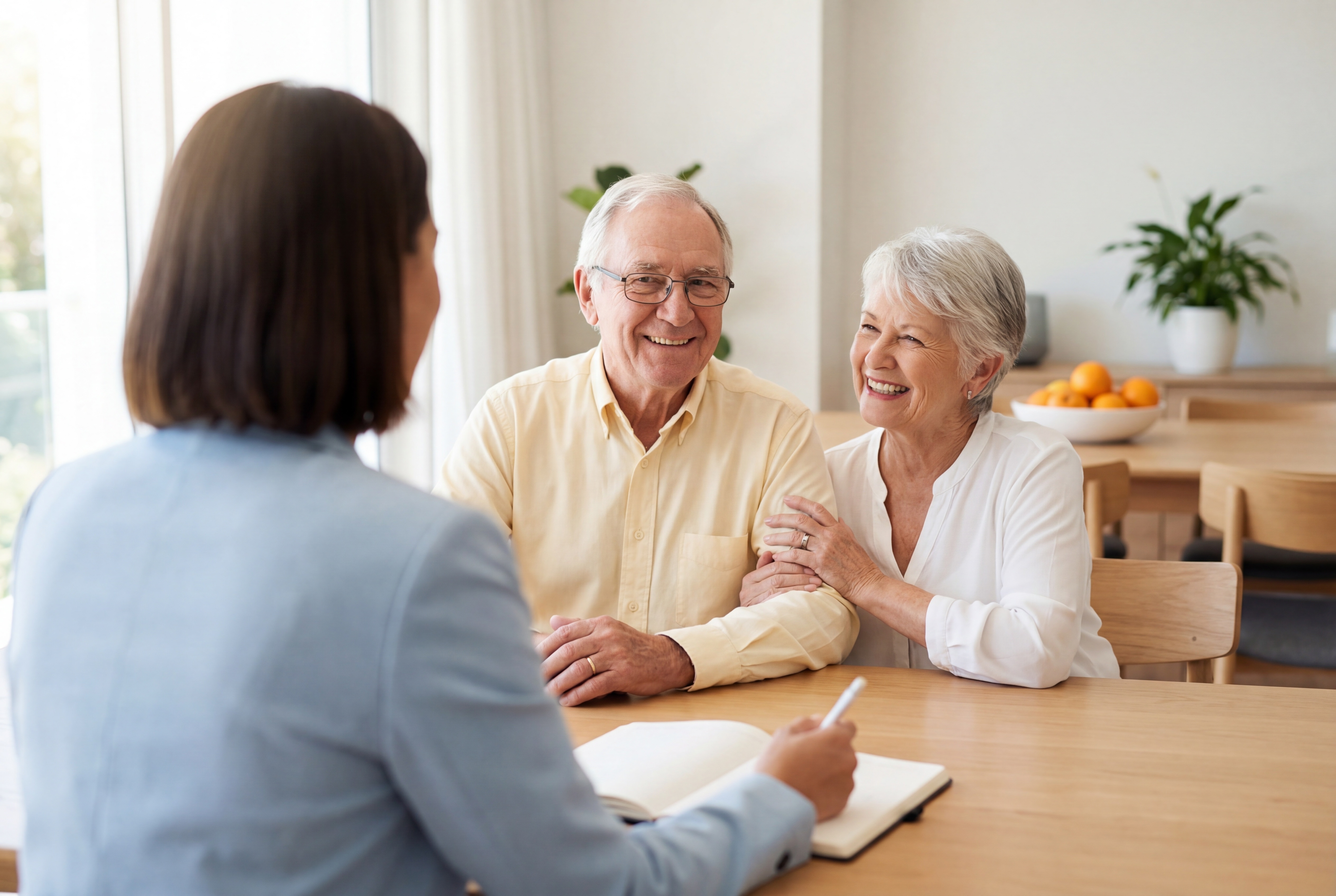 Conseillère échangeant avec un couple de retraités souriants autour d'une table