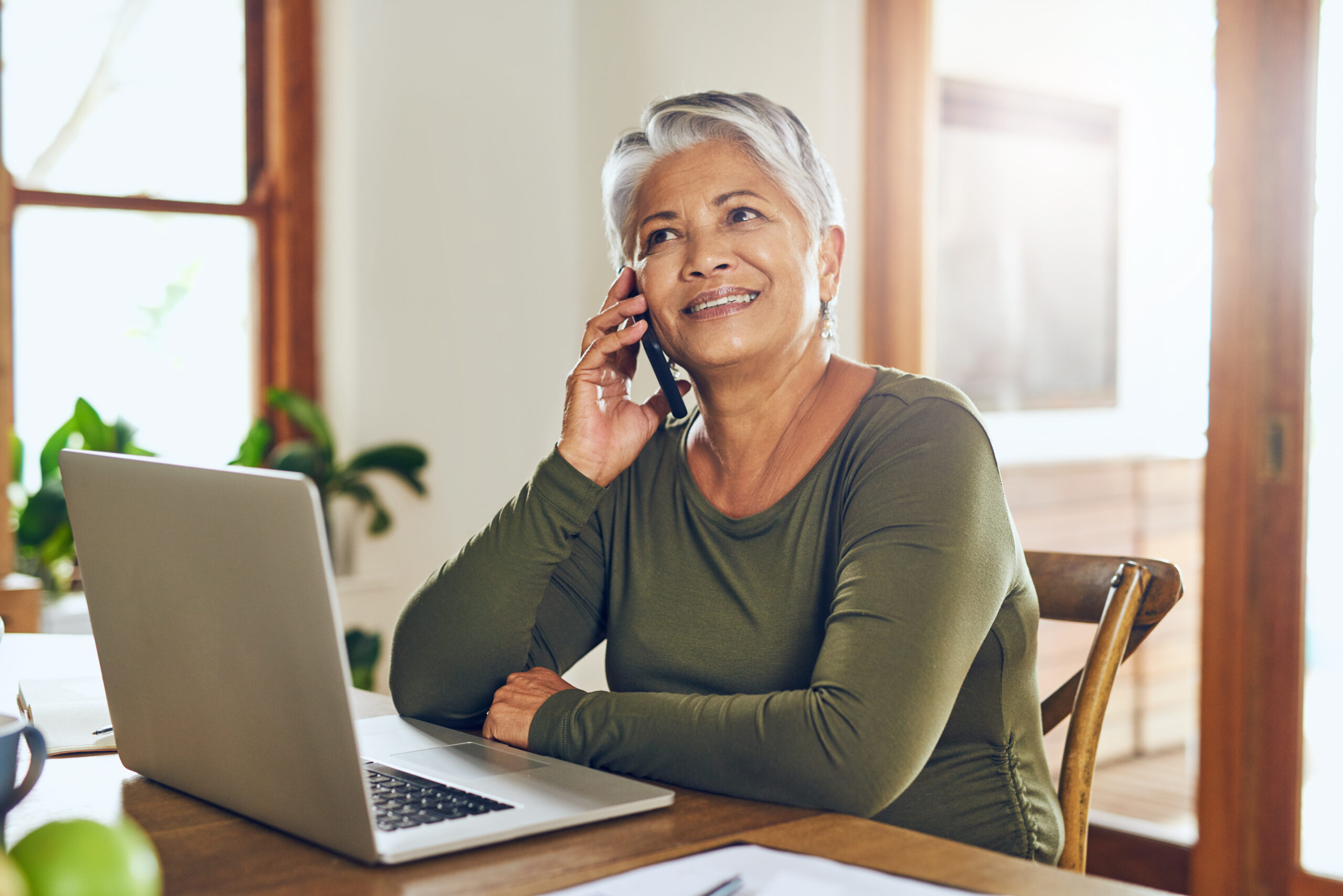 Femme retraitée souriante au téléphone avec un conseiller, chez elle
